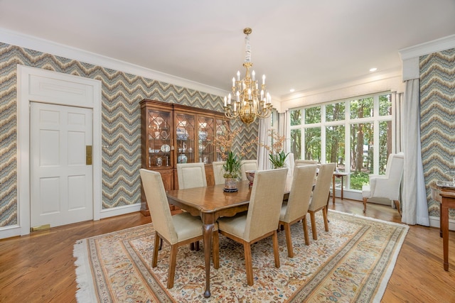 dining space with ornamental molding, light wood-type flooring, and a notable chandelier