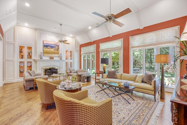 living room with vaulted ceiling with beams, a wealth of natural light, ceiling fan, and light hardwood / wood-style floors