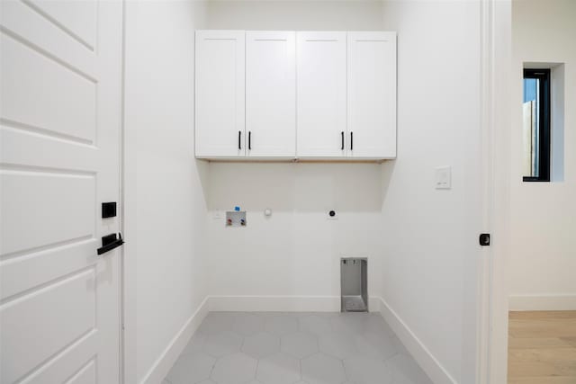 clothes washing area with hookup for a gas dryer, hookup for a washing machine, light tile patterned floors, electric dryer hookup, and cabinets