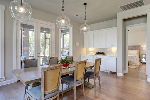 dining space with light hardwood / wood-style floors and beverage cooler