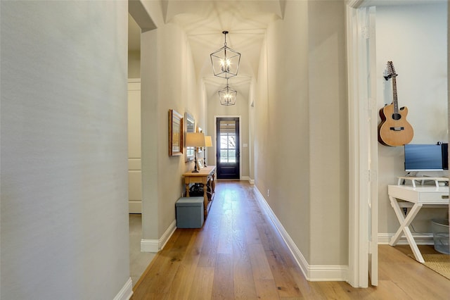 hall with hardwood / wood-style flooring and an inviting chandelier