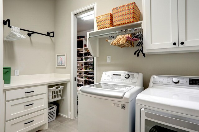 clothes washing area featuring washing machine and dryer, light tile patterned flooring, and cabinets