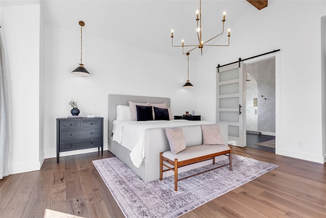 bedroom featuring a barn door, wood finished floors, and baseboards