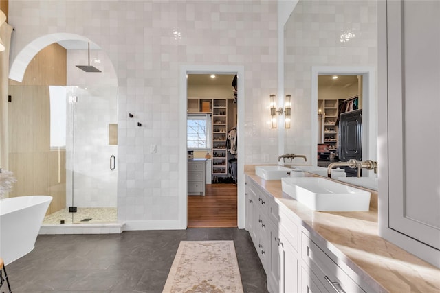 bathroom with tile patterned flooring, vanity, tile walls, and plus walk in shower