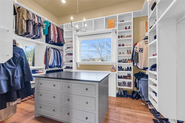 spacious closet featuring light hardwood / wood-style flooring and a chandelier