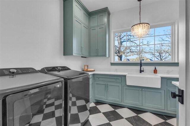 washroom with a sink, cabinet space, tile patterned floors, washing machine and clothes dryer, and an inviting chandelier