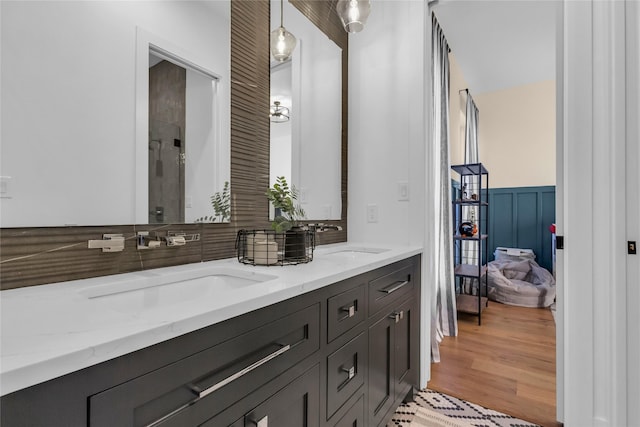 bathroom featuring double vanity, wainscoting, a sink, and wood finished floors