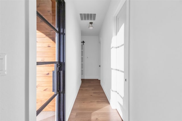 hallway featuring baseboards, visible vents, and light wood-style floors