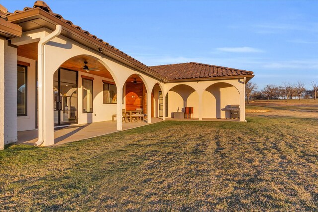 rear view of house featuring a lawn, a patio area, ceiling fan, and an outdoor kitchen