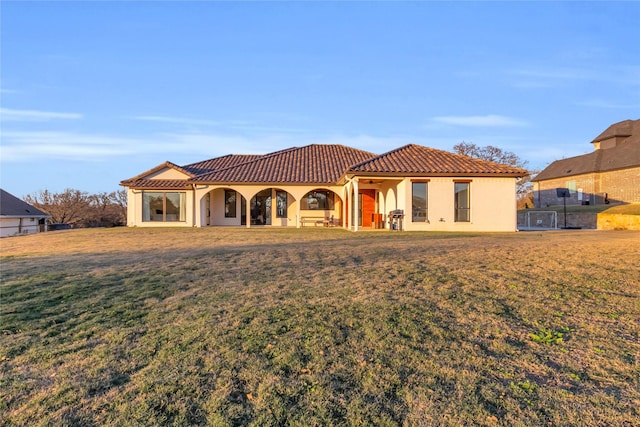 mediterranean / spanish-style house featuring a tiled roof, a front lawn, and stucco siding