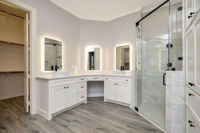 bathroom with hardwood / wood-style floors, vanity, a shower with door, and ornamental molding