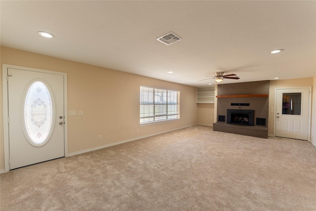 unfurnished living room with ceiling fan, light carpet, and a fireplace