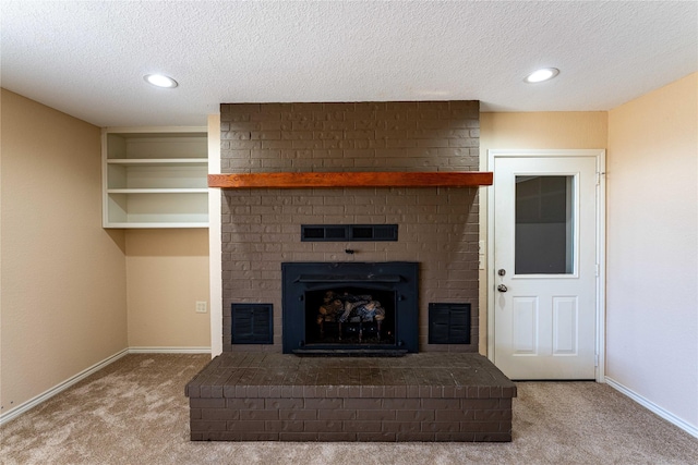 unfurnished living room featuring built in shelves, carpet, a textured ceiling, and a brick fireplace