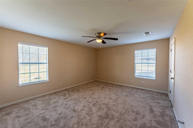 carpeted empty room with ceiling fan, a healthy amount of sunlight, and a textured ceiling