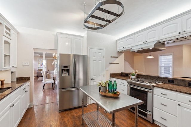 kitchen with appliances with stainless steel finishes, dark hardwood / wood-style floors, pendant lighting, dark stone counters, and white cabinets