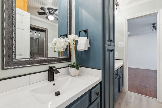 bathroom featuring vanity, hardwood / wood-style flooring, ceiling fan, and ornamental molding