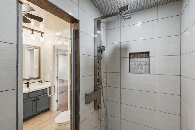 bathroom with vanity, hardwood / wood-style flooring, toilet, tile walls, and a shower with shower door