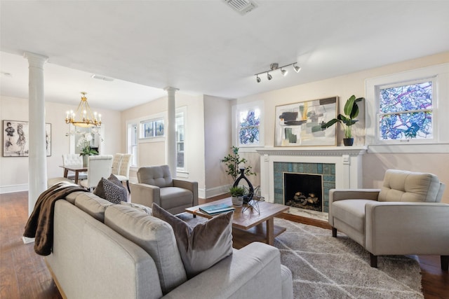 living room with a fireplace, hardwood / wood-style flooring, ornate columns, and a notable chandelier