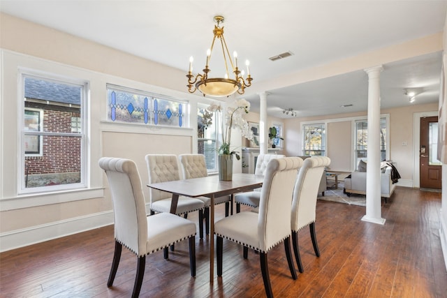 dining area featuring an inviting chandelier, dark wood-type flooring, and ornate columns