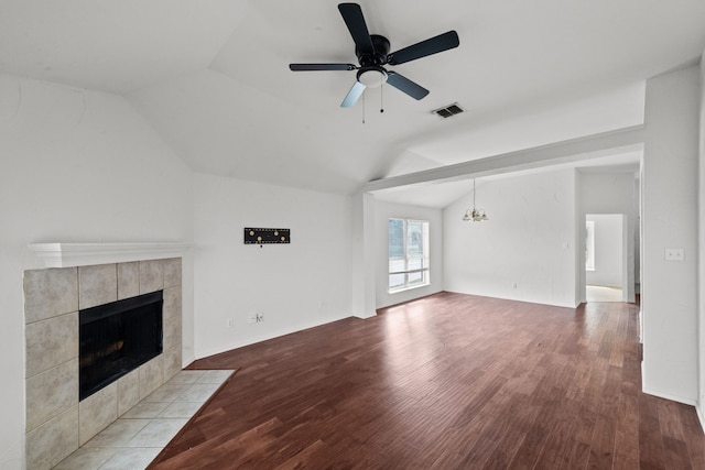 unfurnished living room with ceiling fan with notable chandelier, a tiled fireplace, light hardwood / wood-style flooring, and vaulted ceiling