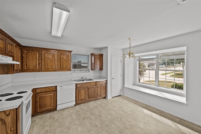 kitchen featuring sink, pendant lighting, white appliances, and a notable chandelier