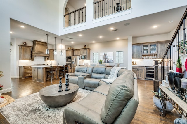 living room with hardwood / wood-style flooring, a towering ceiling, and beverage cooler