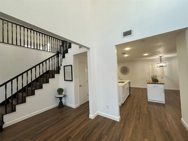 stairs featuring hardwood / wood-style floors, a notable chandelier, and sink