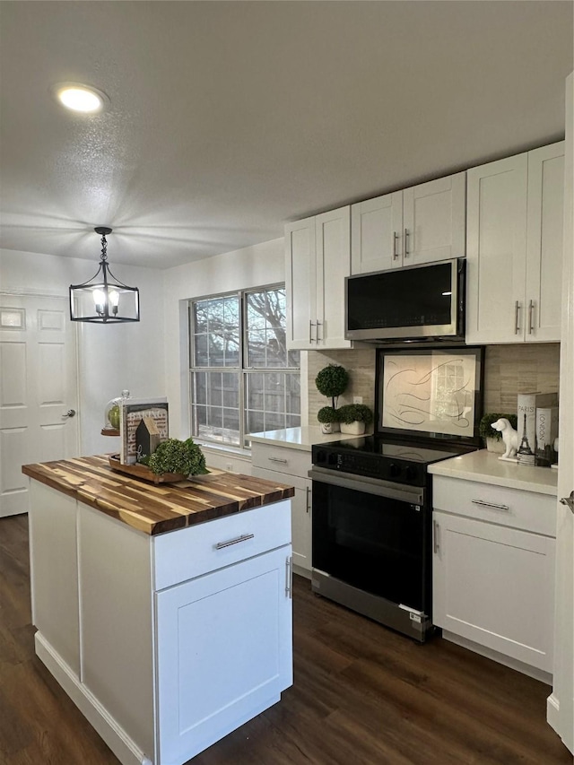 kitchen featuring white cabinets, hanging light fixtures, appliances with stainless steel finishes, tasteful backsplash, and butcher block counters