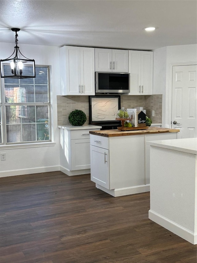 kitchen with dark hardwood / wood-style floors, white cabinetry, backsplash, and hanging light fixtures