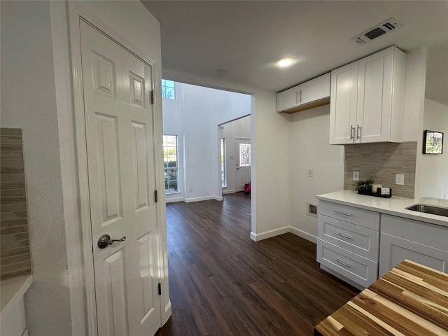 kitchen with backsplash, white cabinetry, dark hardwood / wood-style flooring, and sink