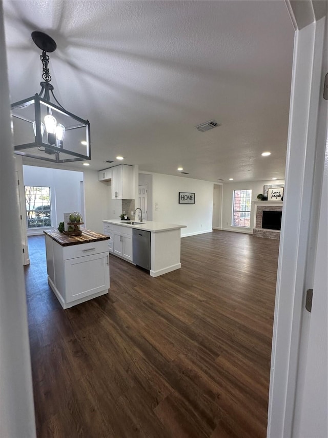 kitchen featuring white cabinetry, a center island, sink, hanging light fixtures, and stainless steel dishwasher