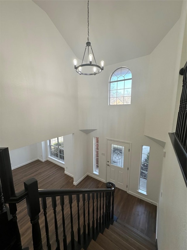 foyer entrance with dark hardwood / wood-style flooring, high vaulted ceiling, and a notable chandelier