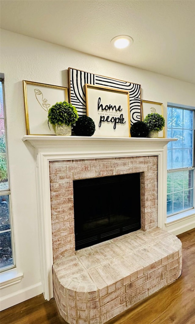 interior details with wood-type flooring and a brick fireplace