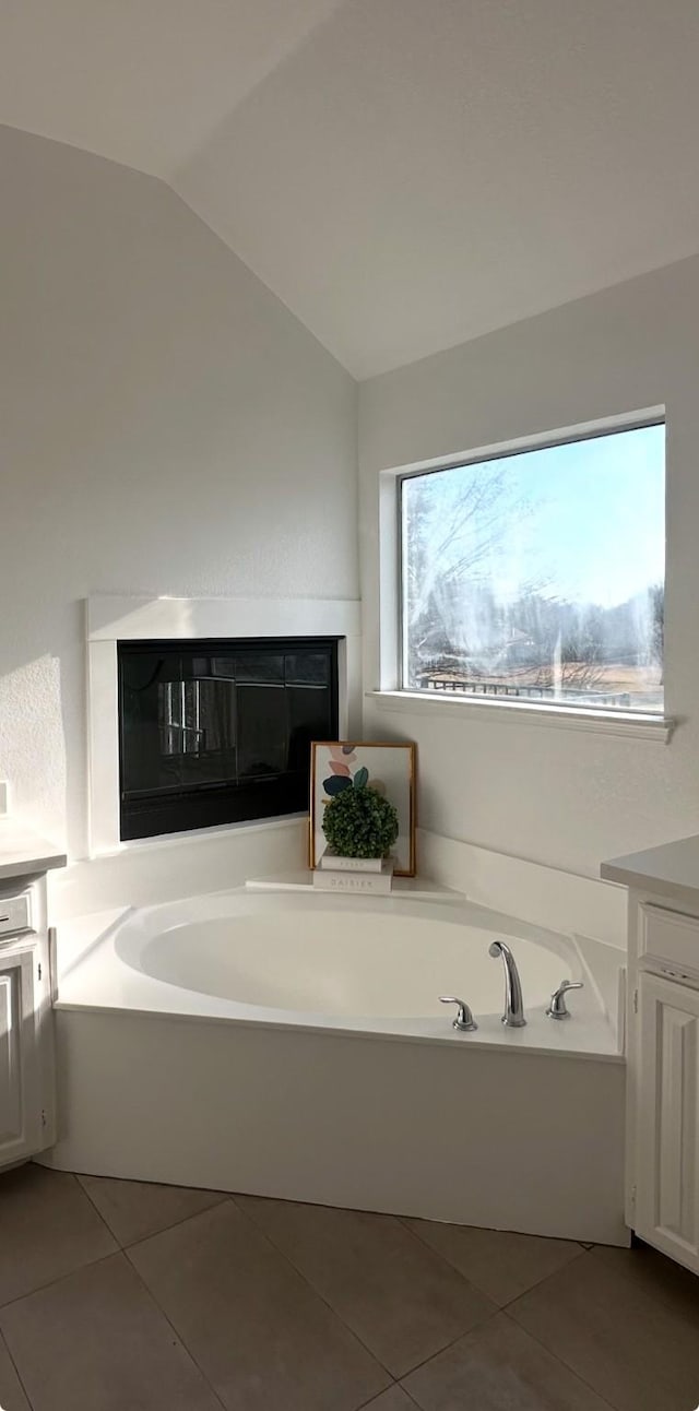 bathroom featuring tile patterned floors, vanity, vaulted ceiling, and a bathing tub