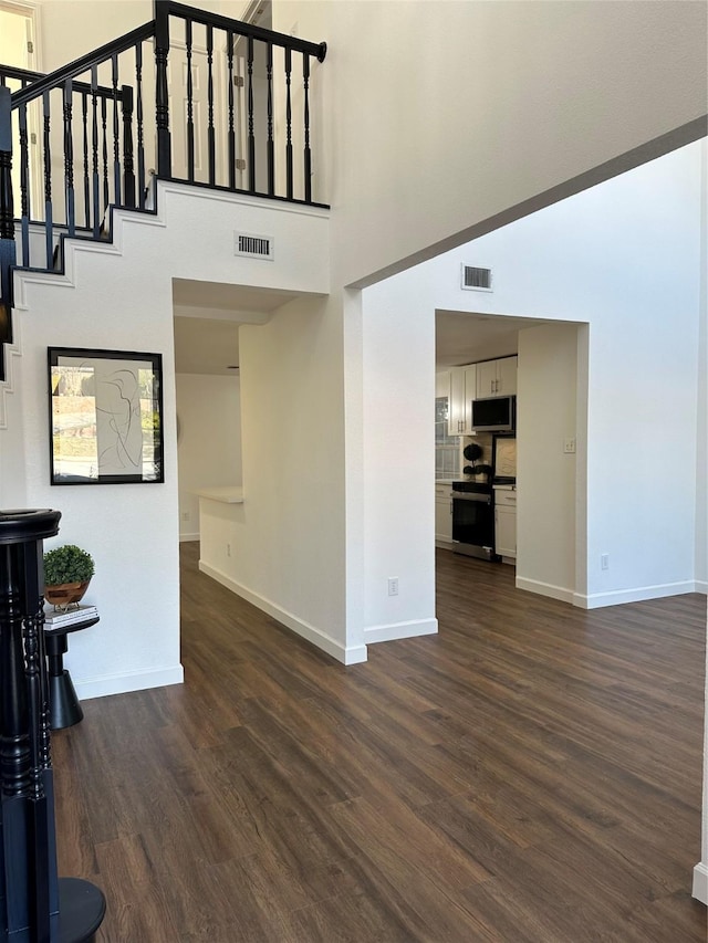 interior space featuring a towering ceiling and dark hardwood / wood-style floors