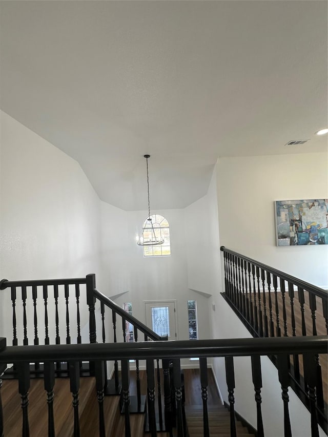 stairway featuring a notable chandelier and wood-type flooring