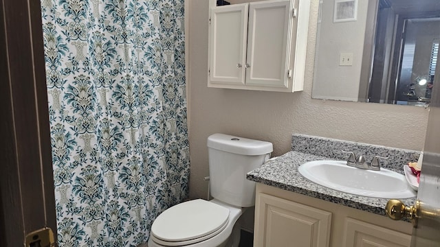 bathroom featuring vanity, toilet, and walk in shower