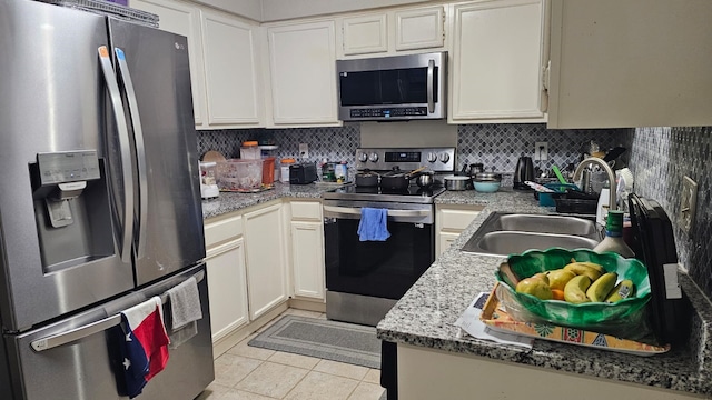 kitchen with decorative backsplash, sink, light tile patterned floors, and appliances with stainless steel finishes