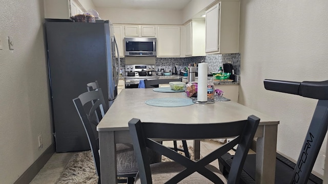 kitchen with white cabinets, backsplash, stainless steel appliances, and kitchen peninsula