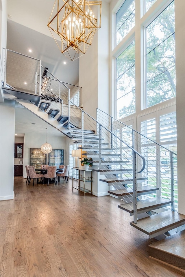 stairway featuring a high ceiling, hardwood / wood-style flooring, and a notable chandelier