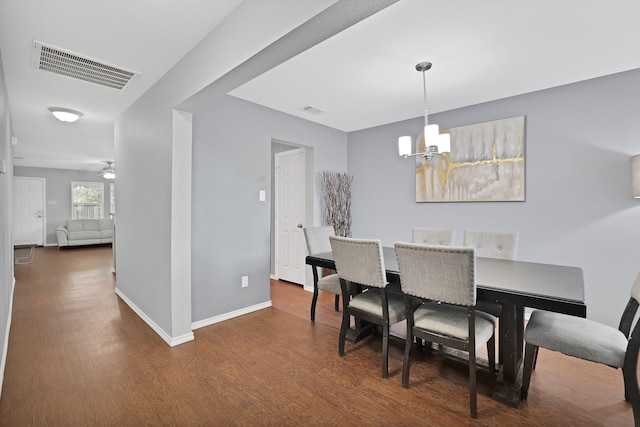 dining space with dark wood-type flooring and ceiling fan with notable chandelier