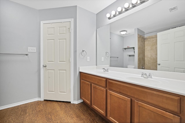 bathroom featuring tiled shower, wood-type flooring, toilet, and vanity