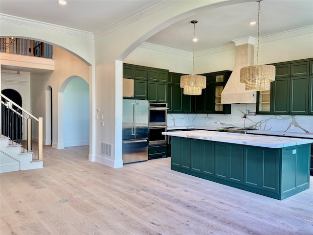 kitchen with light wood-style flooring, green cabinetry, stainless steel appliances, visible vents, and premium range hood