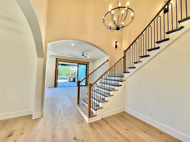 entrance foyer featuring baseboards, light wood finished floors, stairs, and a high ceiling