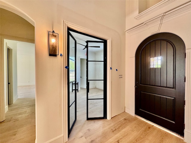 entryway with light wood-style floors, baseboards, and arched walkways