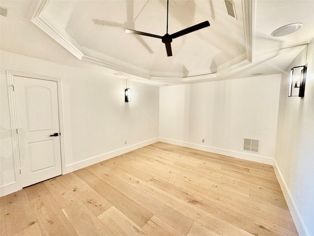 spare room with a raised ceiling, visible vents, ceiling fan, light wood-style floors, and baseboards