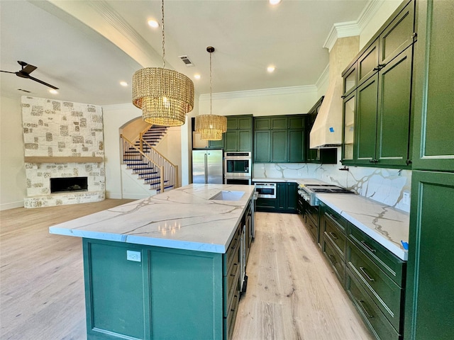 kitchen with green cabinetry, visible vents, stainless steel appliances, a center island, and ornamental molding