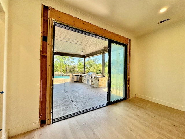 doorway featuring baseboards, visible vents, and wood finished floors