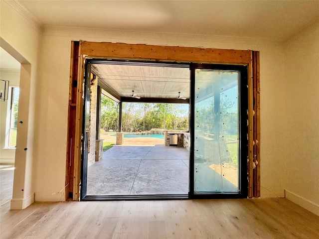 doorway featuring wood finished floors, ornamental molding, and baseboards