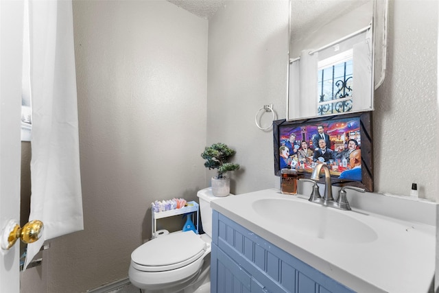 bathroom featuring vanity, a textured ceiling, and toilet